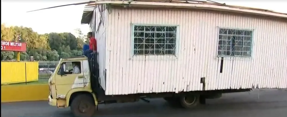 Caminhão transporta casa de madeira com homem no teto do veículo em SC